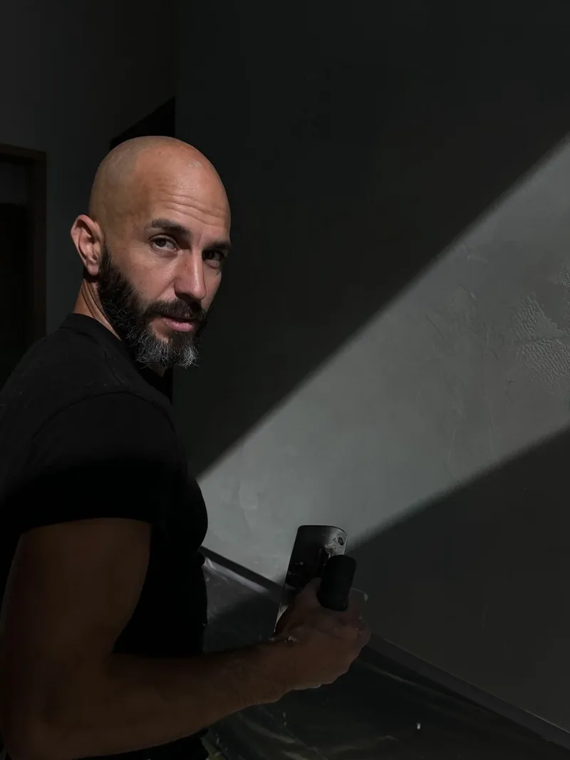 Robert Varga in profile, side lit at the plaster wall