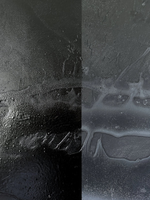 Full-frame macro of drip and splatter relief texture, pitted and glossy beside deep black with fine scratches.