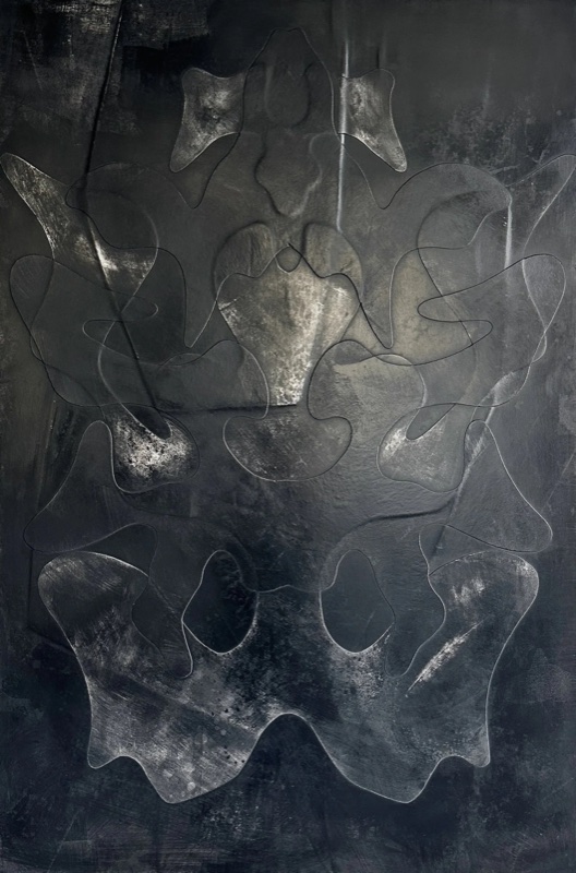 Straight-on shot of a tall dark relief panel on a dark wall, bilateral symmetric organic carved pattern.