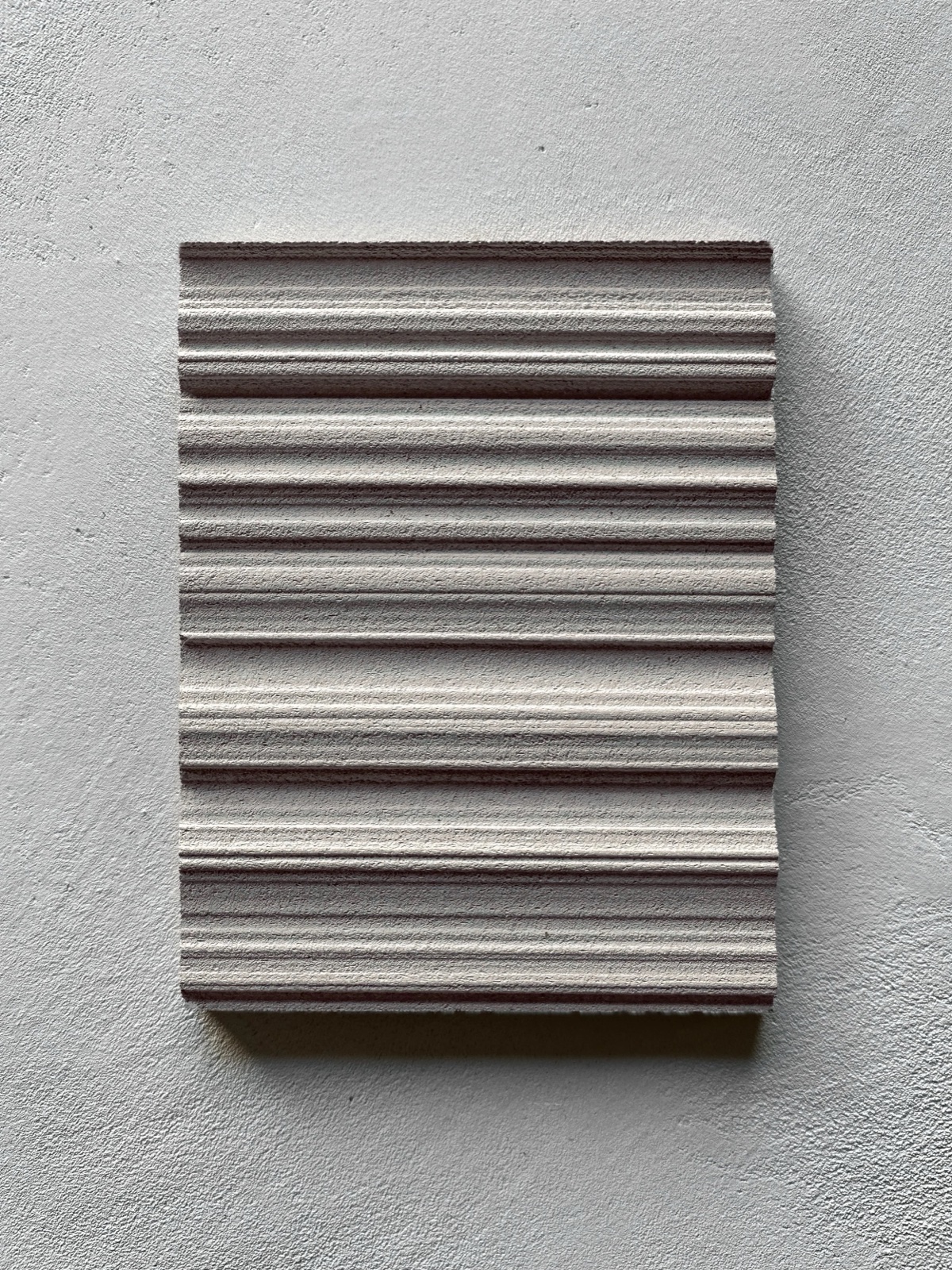 Matte fluted plaster, horizontal reeded grooves under deep raking shadow.