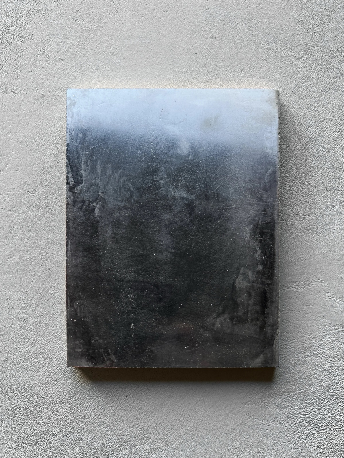 High gloss Venetian plaster sample fading from silver to black in cloudlike mottling.