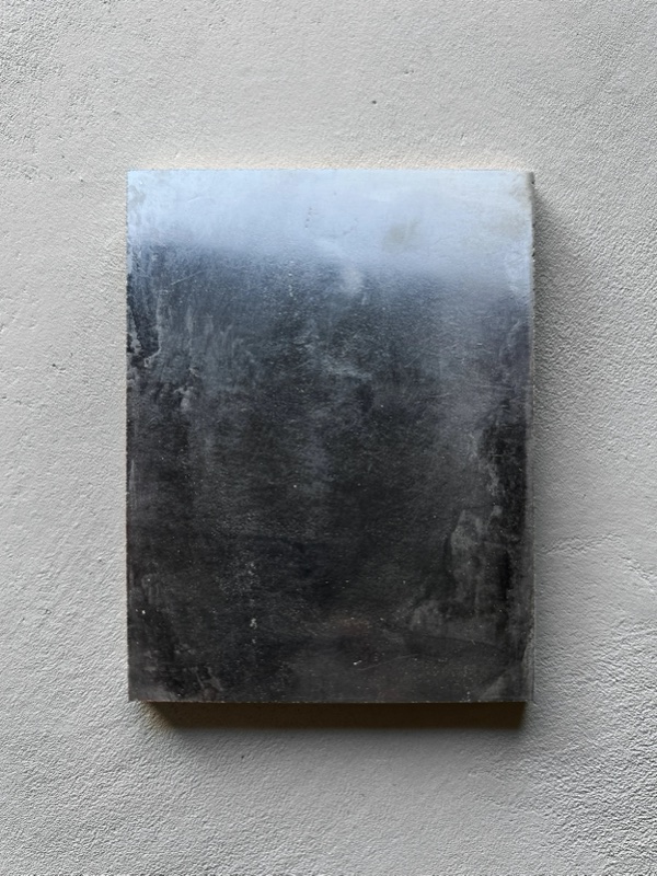 A finish sample panel of high-gloss Venetian plaster showing a cloud-like tonal gradient from silver to black.