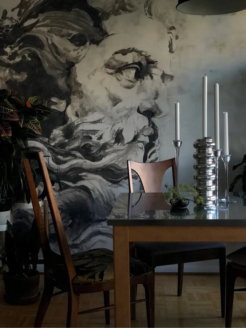 Large hand-painted ink-wash mural of a classical bearded figure behind a dining table with silver candlesticks