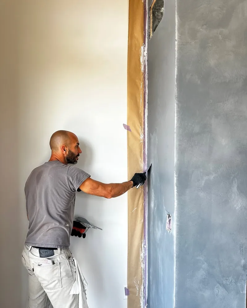 Plasterer applying plaster to a fireplace by hand, mid-install