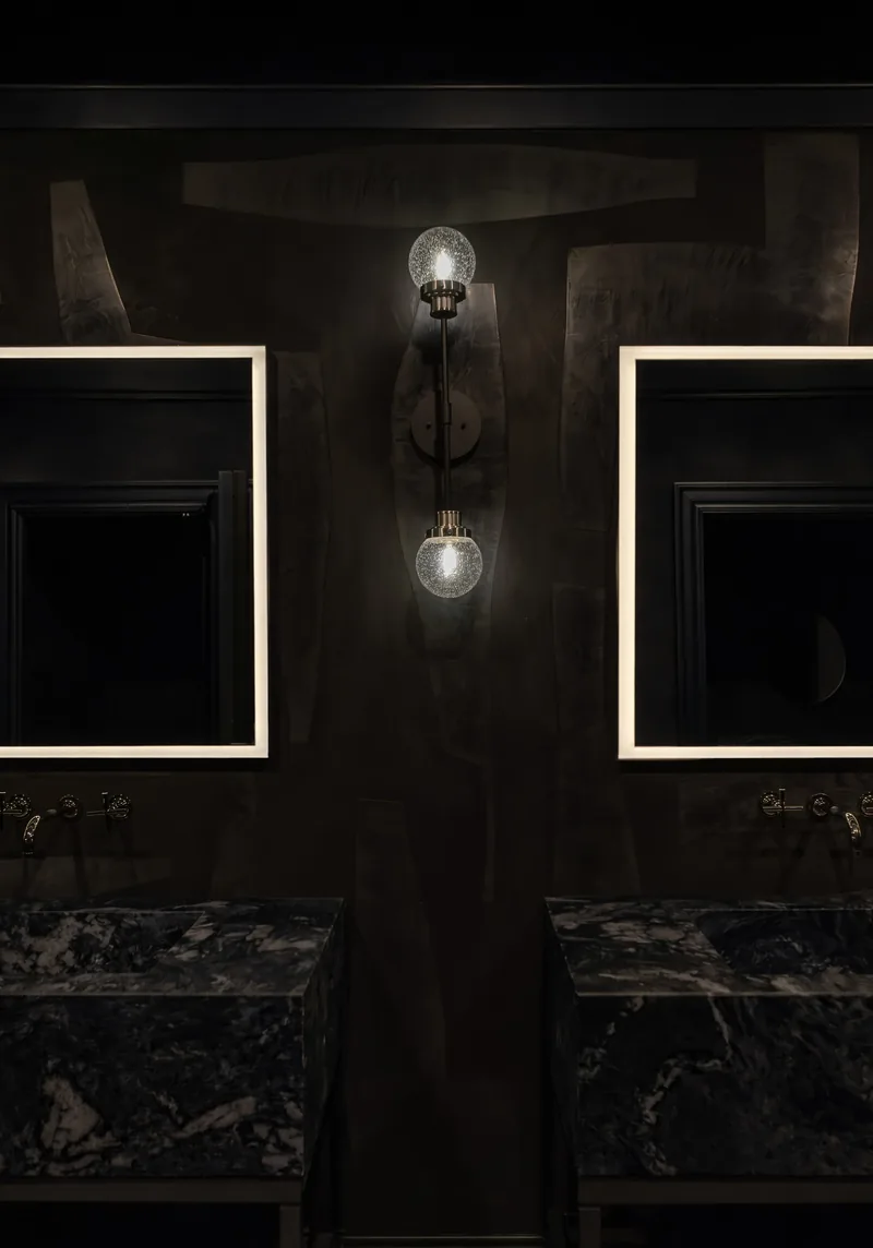 Powder room in hand-troweled dark plaster, twin stone sinks and seeded-glass sconce